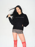 A woman modeling a black hoodie with 'internet finds' printed in white across the chest, paired with a leopard-print mini skirt and red thigh-high socks, against a plain white studio background.