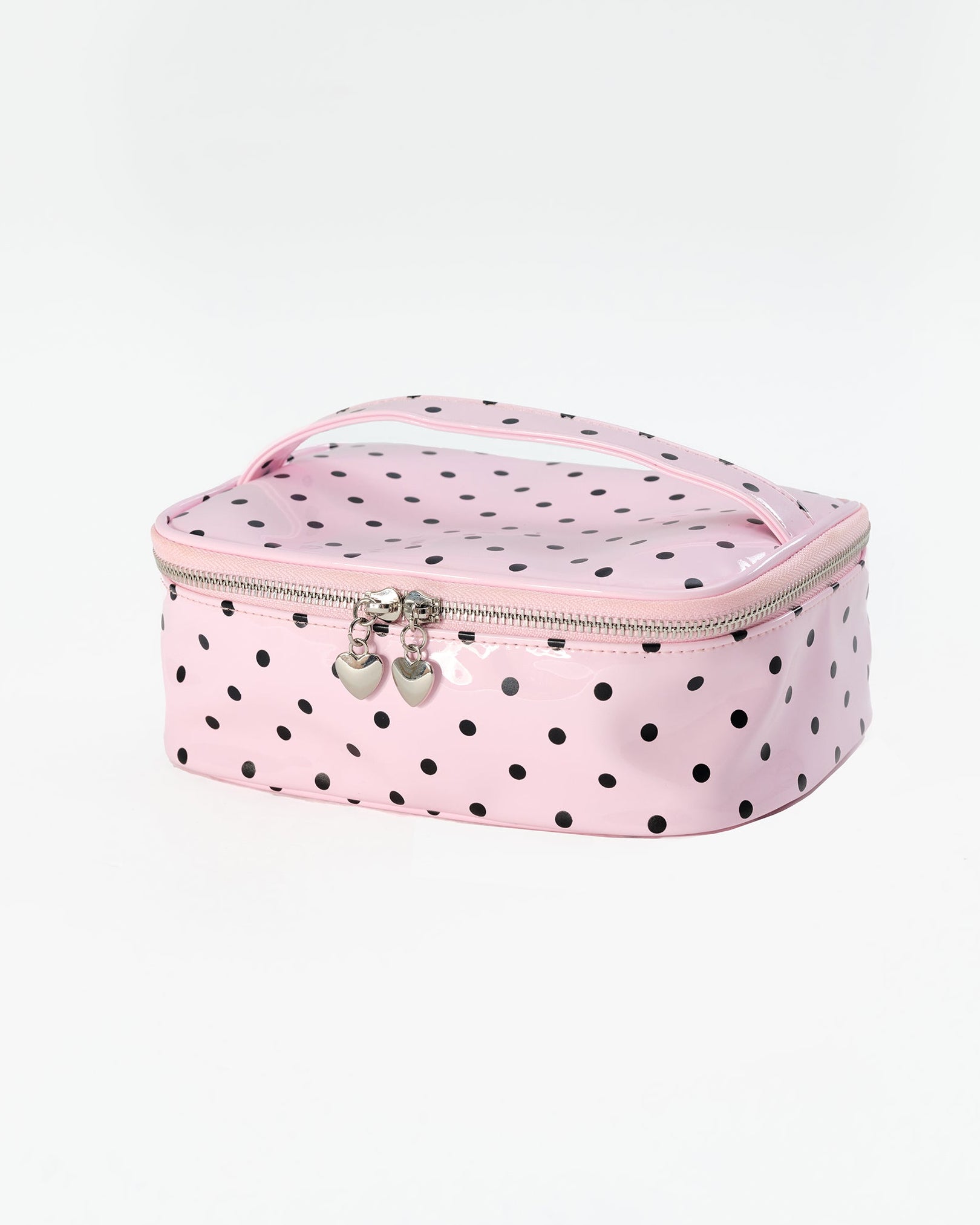A pink zippered makeup bag with black polka dots, featuring a top handle and silver heart-shaped zipper pulls, set against a plain white background.