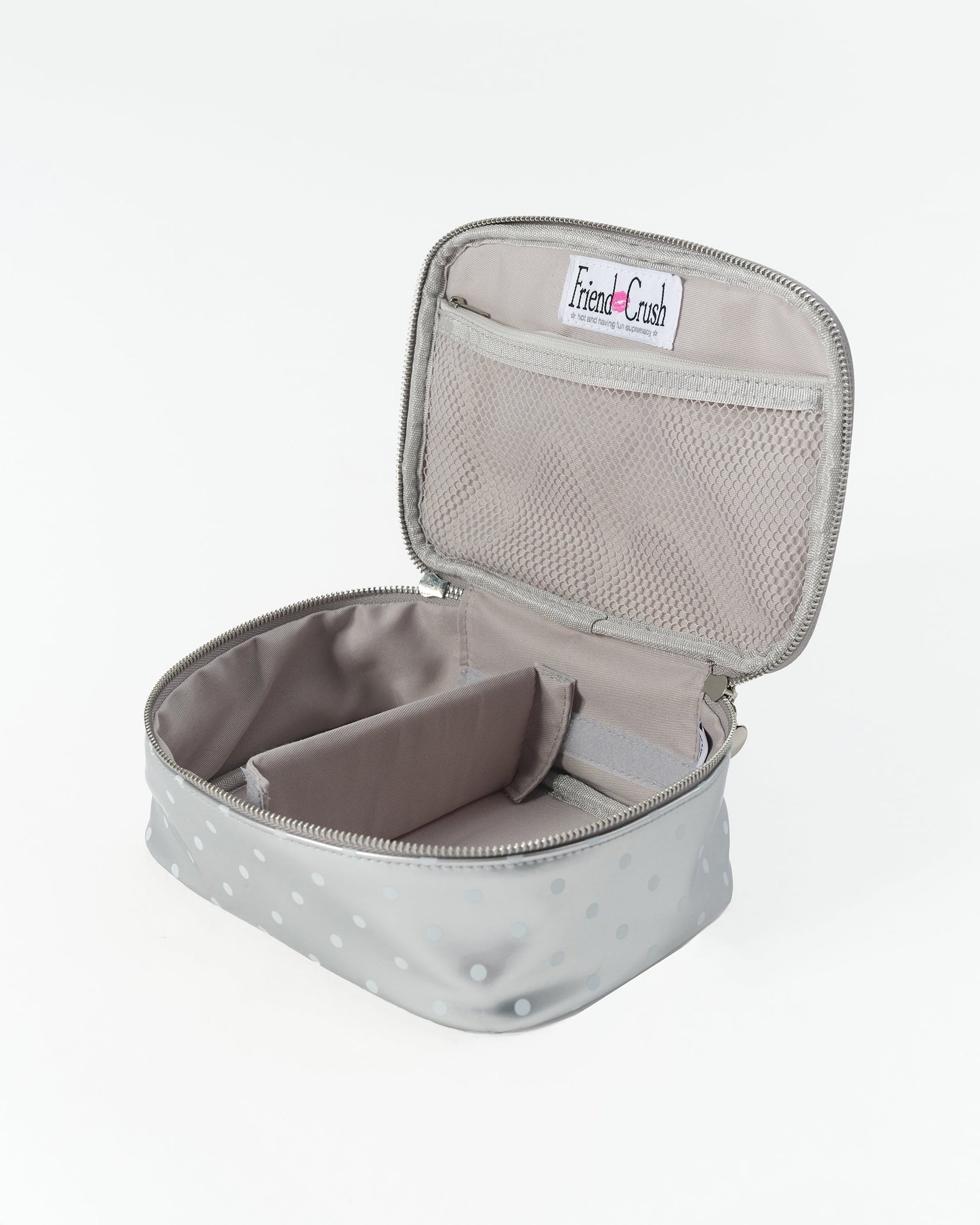A gray zippered travel organizer case with a polka dot pattern, shown open to reveal its interior compartments and a mesh pocket on the lid. A 'Friend Crush' brand label is visible inside.