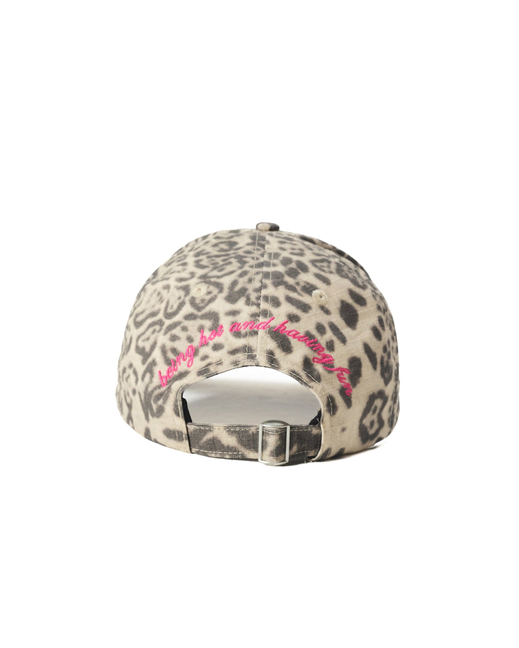 A baseball cap with a beige and gray leopard print pattern, featuring a bright pink embroidered arch on the back above the metal buckle closure.